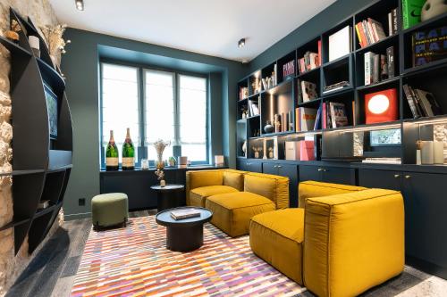 a living room with yellow chairs and bookshelves at Hôtel Amoi Paris in Paris