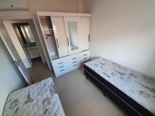 um quarto com 2 camas, uma cómoda e um espelho em Apto na praia de Palmas, próximo ao mar, climatizado e com piscina em Governador Celso Ramos