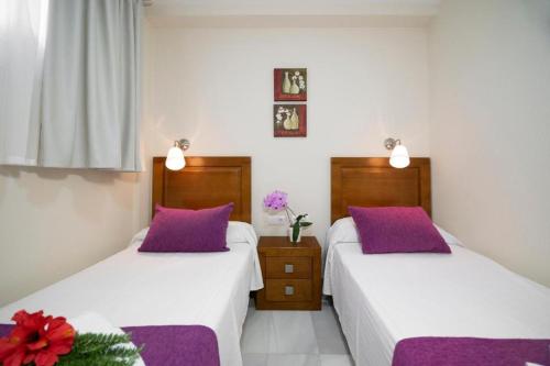 two beds in a room with purple pillows at APARTAMENTOS MAR Y GOLF in Roquetas de Mar