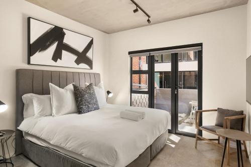 um quarto com uma cama grande e uma janela em Hyde Park House Apartments em Joanesburgo