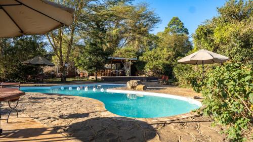 a swimming pool with an umbrella in a yard at Yellowwood House in Nakuru