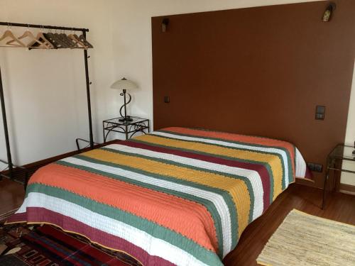 um quarto com uma cama com um cobertor listrado colorido em Gite de la Renaissance, Binic , Bretagne em Binic