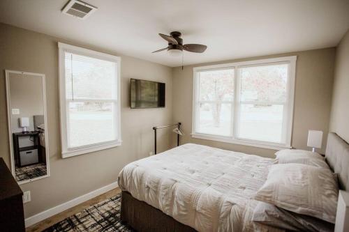 a bedroom with a bed with a ceiling fan and two windows at The Turquoise Door Modern Rustic in Town of Lexington in Lexington