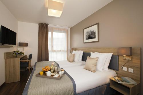 a hotel room with a bed with a tray of food on it at Residhome Paris Issy Les Moulineaux in Issy-les-Moulineaux