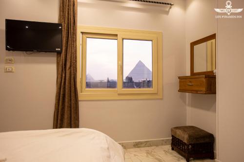 a bedroom with a bed and a window with a view of the pyramids at Life Pyramids Inn in Cairo