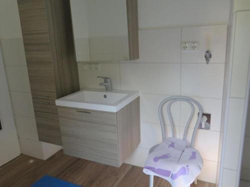 La salle de bains est pourvue d'un lavabo et d'une chaise. dans l'établissement Ferienwohnung Aiblinger, à Frasdorf