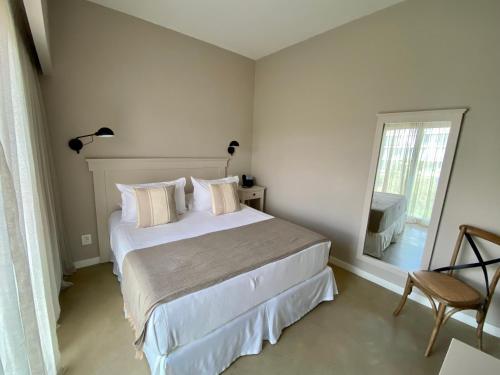 a white bedroom with a bed and a mirror at Serena Hotel - Punta del Este - Unico sobre la Playa in Punta del Este