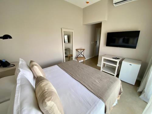 a bedroom with a white bed and a television at Serena Hotel - Punta del Este - Unico sobre la Playa in Punta del Este