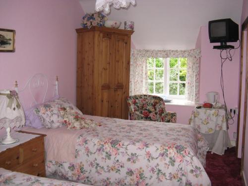a bedroom with a bed and a chair and a window at East Farm House B&B in Abbotsbury