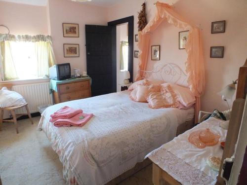 a bedroom with a large white bed with pink sheets at East Farm House B&B in Abbotsbury