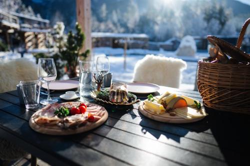 a wooden table with plates of food and wine glasses at Lakeside Petzen Glamping in Unterlibitsch