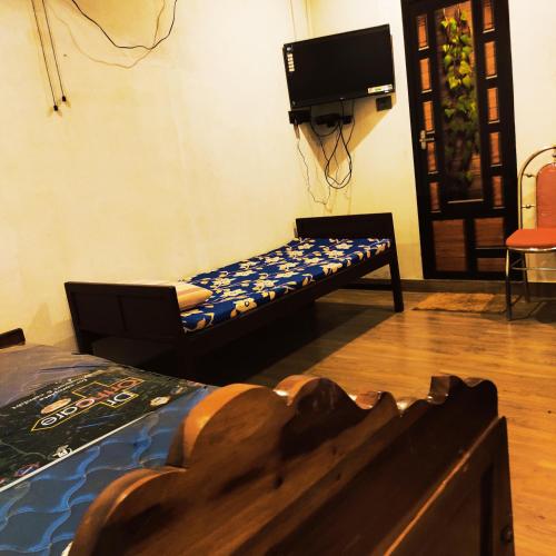 a bedroom with a bed and a tv on the wall at Munroe Inn Homestay in Kollam