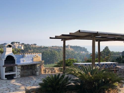 a stone patio with a pizza oven and an umbrella at Scopello Guidaloca Villas in Scopello