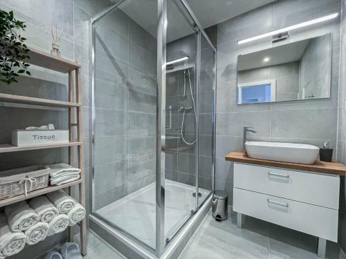 a bathroom with a glass shower and a sink at LAWIS Apartments in Poprad