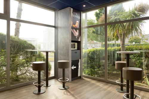 a room with large windows and stools at Ibis Budget Saint Malo Centre in Saint Malo