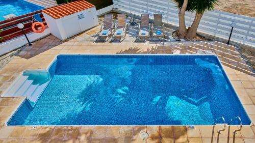 a blue swimming pool with chairs and a palm tree at Villa Shiva by Ezoria Villas in Coral Bay