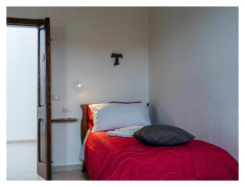 a bedroom with a bed with a red blanket at Monastero Santa Chiara CpF in Oristano