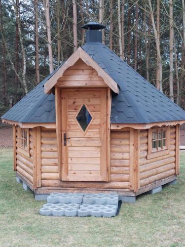a large wooden cabin with a black roof at Leśna Osada przy Suntago Park in Krzyżówka
