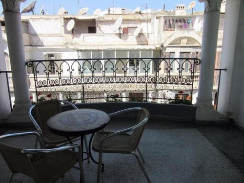 a patio with a table and chairs and a balcony at Hôtel Transatlantique in Casablanca