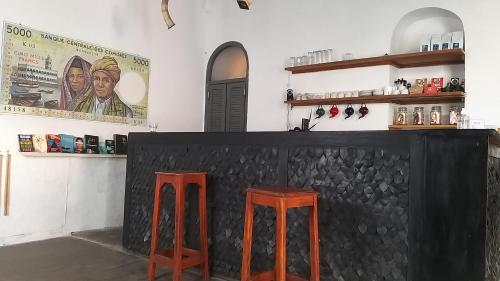 a bar with two red stools in a room at Ndar Ndar House in Saint-Louis