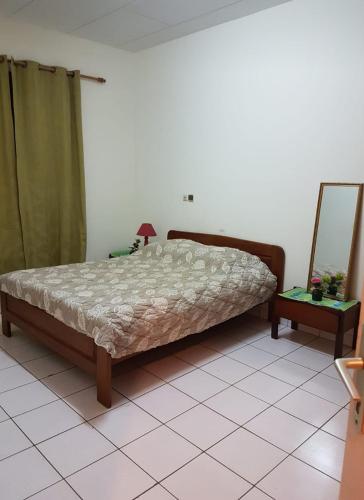 a bedroom with a bed and a mirror on a tiled floor at Résidence Lina in Libreville