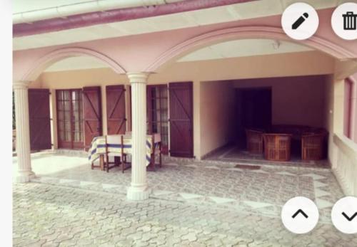 a house with a porch with a table and columns at Résidence Lina in Libreville