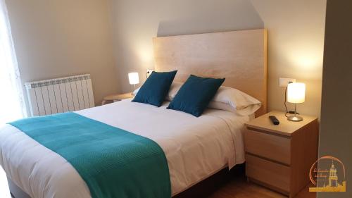 a bedroom with a large bed with blue pillows at EL CAPRICHO DEL BURGO in El Burgo de Osma