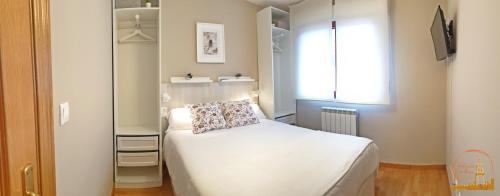 a small bedroom with a white bed and a window at EL CAPRICHO DEL BURGO in El Burgo de Osma