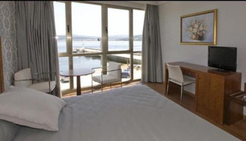 Pokój z łóżkiem, biurkiem i balkonem. w obiekcie Hotel As Brisas do Freixo w mieście O Freixo