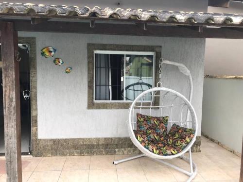 a white chair with a pillow on a porch at Casa com piscina, wifi e churrasqueira em unamar. in Tamoios