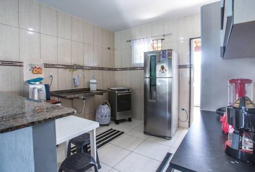 a kitchen with a stainless steel refrigerator in it at Casa com piscina, wifi e churrasqueira em unamar. in Tamoios