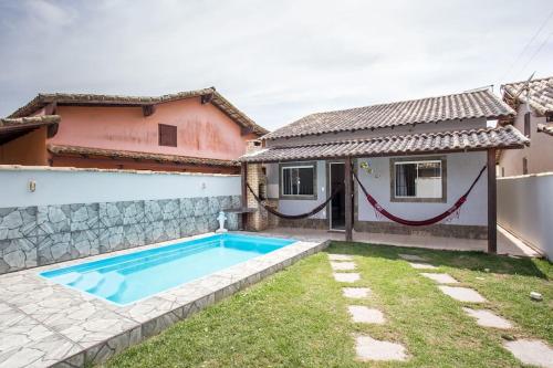 a swimming pool in a yard next to a house at Casa com piscina, wifi e churrasqueira em unamar. in Tamoios