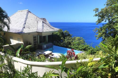 a house with a swimming pool next to the ocean at Arc en Ciel in Soufrière