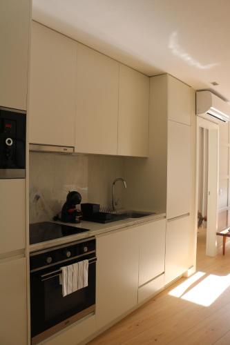 a kitchen with white cabinets and a stove top oven at Villa Graça -Hostels and Apartments in Santarém