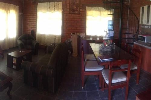 a living room with a couch and a table and chairs at Cabaña a orillas del Lago in Tarija