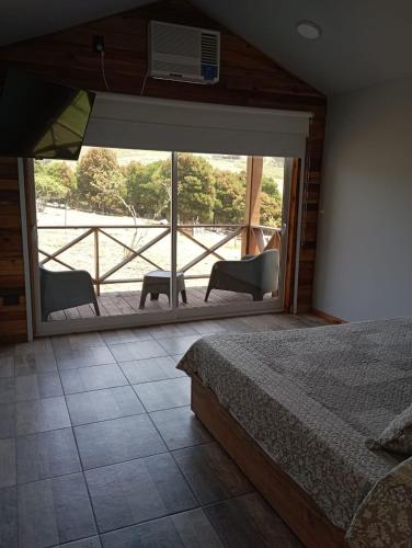 a bedroom with a bed and a view of a balcony at Cabañas Valle de los Ciervos in Tandil