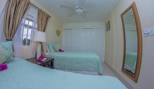 a bedroom with two beds and a mirror and a fan at Lantana Barbados Condos in Saint James
