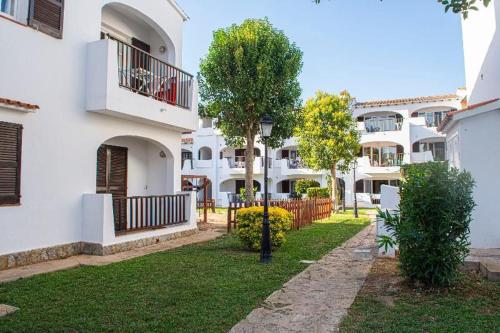 a row of white apartment buildings with trees in the yard at Apartamento Can escaragoli in Cala en Porter