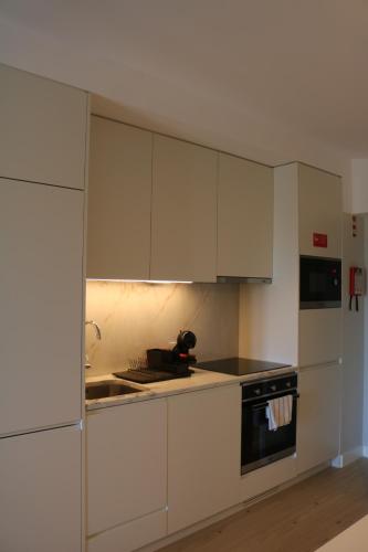 a white kitchen with white cabinets and a sink at Villa Graça -Hostels and Apartments in Santarém