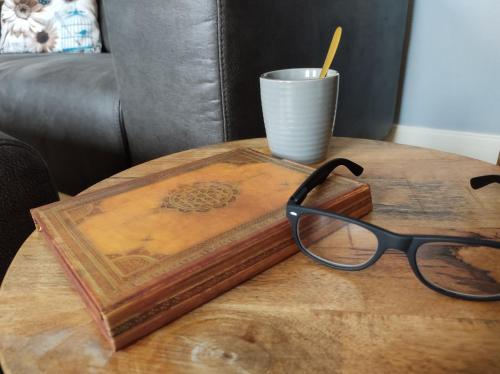 a table with a book and a cup and a pair of glasses at Minicamping und B&B Apartment Hintergarten in Niederorschel