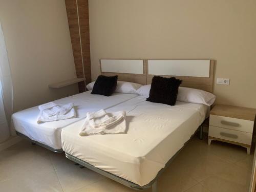 - 2 lits dans une chambre avec des serviettes dans l'établissement Apartamentos La Unión, à Arroyo de la Luz
