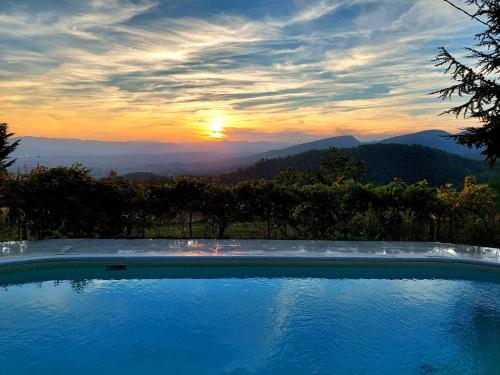 a swimming pool with the sunset in the background at Villa Giuliana B&B in Scarperia