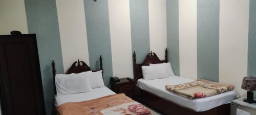 two beds in a room with striped walls at Hotel Shelton Palace in Multan