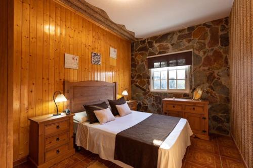 1 dormitorio con cama y pared de piedra en Villa Sara, en Cardón