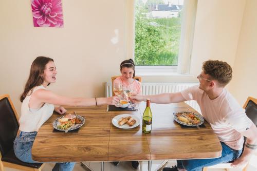 Enniskillen Watersedge Apartments في إنيسكيلين: مجموعة من الناس يجلسون حول طاولة يأكلون الطعام
