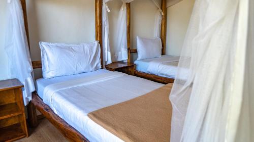 two beds in a small room with white sheets at The Senna House in Nakuru