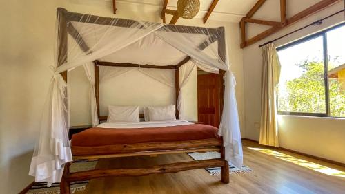 a bedroom with a canopy bed and a window at The Senna House in Nakuru