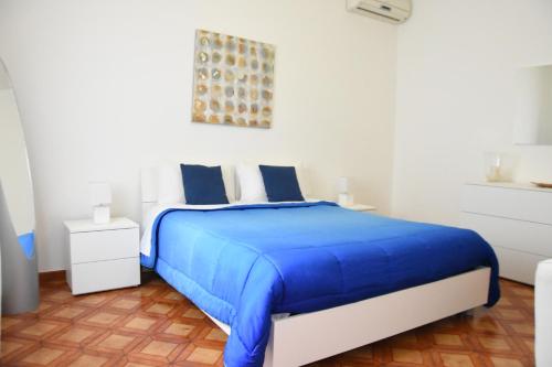 een witte slaapkamer met een blauw bed met blauwe lakens bij Casa de lidzia2 in Cisternino
