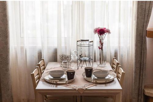 a table with plates and bowls and a vase of flowers at Casa de lidzia2 in Cisternino