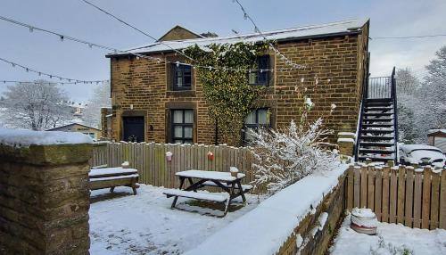 Winewall的住宿－Trawden Arms Community Owned Pub，雪地里带长凳和桌子的房子